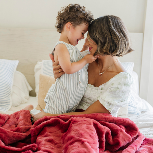 A mother and her son have a red luxurious patterned faux fur throw blanket that is a Saranoni blanket. This ultra-soft, plush throw blanket adds a touch of elegance and warmth to any space, perfect as a soft throw blanket or fluffy blanket for lounging. Ideal for those seeking a high-quality artificial fur blanket or luxury blanket, this versatile and stylish soft blanket enhances both comfort and decor. Shop the best blankets and throws for ultimate relaxation and cozy vibes.