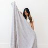 A woman holds a light gray luxurious patterned faux fur extra large throw blanket that is a Saranoni blanket. This ultra-soft, cozy blanket adds a touch of elegance and warmth to any space, perfect as a soft oversized blanket or fluffy blanket for lounging. Ideal for those seeking a high-quality artificial fur blanket or luxury blanket, this versatile and stylish soft blanket enhances both comfort and decor. Shop the best blankets and throws for ultimate relaxation and cozy vibes.