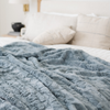 A dusty blue luxurious patterned faux fur throw blanket that is a Saranoni blanket is on a bed. This ultra-soft, plush throw blanket adds a touch of elegance and warmth to any space, perfect as a soft throw blanket or fluffy blanket for lounging. Ideal for those seeking a high-quality artificial fur blanket or luxury blanket, this versatile and stylish soft blanket enhances both comfort and decor. Shop the best blankets and throws for ultimate relaxation and cozy vibes.