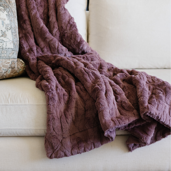 A dusty mauve luxurious patterned faux fur throw blanket that is a Saranoni blanket is on a couch. This ultra-soft, plush throw blanket adds a touch of elegance and warmth to any space, perfect as a soft throw blanket or fluffy blanket for lounging. Ideal for those seeking a high-quality artificial fur blanket or luxury blanket, this versatile and stylish soft blanket enhances both comfort and decor. Shop the best blankets and throws for ultimate relaxation and cozy vibes.