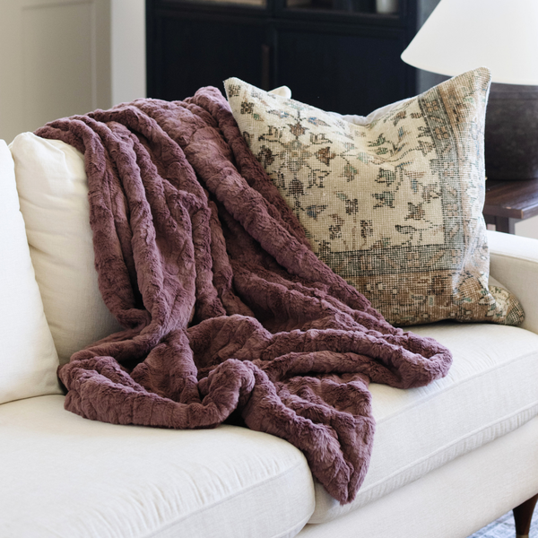 A dusty mauve luxurious patterned faux fur throw blanket that is a Saranoni blanket is draped on a couch. This ultra-soft, plush throw blanket adds a touch of elegance and warmth to any space, perfect as a soft throw blanket or fluffy blanket for lounging. Ideal for those seeking a high-quality artificial fur blanket or luxury blanket, this versatile and stylish soft blanket enhances both comfort and decor. Shop the best blankets and throws for ultimate relaxation and cozy vibes.