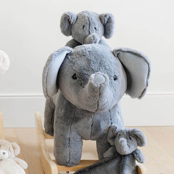 A delightful trio of gray elephant stuffed animals, featuring a large plush elephant rocker in the foreground, a smaller elephant sitting on its back, and a tiny one beside them. The soft, cuddly textures and adorable designs make these plush toys perfect companions for children. This charming display highlights the joy of cuddling with plush animals while showcasing the unique rocker, emphasizing their role in nurturing imaginative play and comfort for little ones.