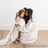 A mother wearing an 'Elf' snuggler is hugging her two daughters. One daughter is wearing an 'Elf' snuggler as well, but the  other sister is holding an 'Elf' blanket. The soft blanket is a luxury blanket and a Saranoni blanket. 