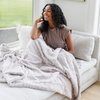 A woman has a very light gray luxurious patterned faux fur throw blanket that is a Saranoni blanket. This ultra-soft, plush throw blanket adds a touch of elegance and warmth to any space, perfect as a soft throw blanket or fluffy blanket for lounging. Ideal for those seeking a high-quality artificial fur blanket or luxury blanket, this versatile and stylish soft blanket enhances both comfort and decor. Shop the best blankets and throws for ultimate relaxation and cozy vibes.