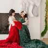 Two young girls by the fireplace with holiday stockings, each wrapped in cozy double ruched blankets—one in festive red and the other in plush green. Perfect for capturing the warmth and joy of the holiday season with luxurious, seasonal decor. The soft blankets are luxury blankets and Saranoni blankets.