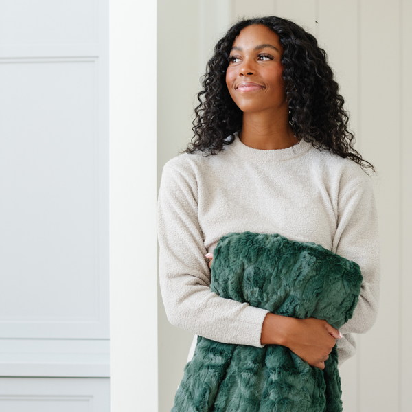 A woman holds a green luxurious patterned faux fur throw blanket that is a Saranoni blanket. This ultra-soft, plush throw blanket adds a touch of elegance and warmth to any space, perfect as a soft throw blanket or fluffy blanket for lounging. Ideal for those seeking a high-quality artificial fur blanket or luxury blanket, this versatile and stylish soft blanket enhances both comfort and decor. Shop the best blankets and throws for ultimate relaxation and cozy vibes.