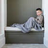 A little boy sits under a Bamboni® blanket by Saranoni. This ultra-soft blanket is a gray blanket and made from a premium blend of bamboo rayon and poly microfiber, offering a lightweight, breathable, and fluffy feel. Perfect as a toddler blanket, luxury blanket, or soft blanket, it adds warmth and elegance to any bedroom and is a kids blanket. Designed for ultimate comfort, this buttery-soft Saranoni blanket is ideal for gifting. Enjoy this cozy blanket for years to come!