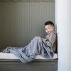 A little boy is sitting under a Bamboni® blanket by Saranoni. This ultra-soft blanket is a gray blanket and made from a premium blend of bamboo rayon and poly microfiber, offering a lightweight, breathable, and fluffy feel. Perfect as a toddler blanket, luxury blanket, or soft blanket, it adds warmth and elegance to any bedroom and is a kids blanket. Designed for ultimate comfort, this buttery-soft Saranoni blanket is ideal for gifting. Enjoy this cozy blanket for years to come!