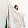 Woman holding an extra large holiday blanket with a holly berry print and green backing, showcasing the blanket’s soft and cozy texture. Great for winter home decor and holiday gifting. The soft blanket is a luxury blanket and a Christmas blanket. 