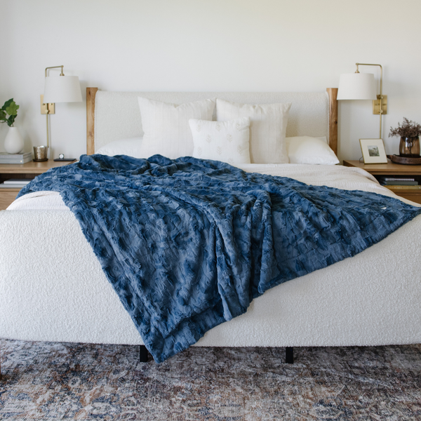 A blue luxurious patterned faux fur throw blanket that is a Saranoni blanket is draped on a bed. This ultra-soft, plush throw blanket adds a touch of elegance and warmth to any space, perfect as a soft throw blanket or fluffy blanket for lounging. Ideal for those seeking a high-quality artificial fur blanket or luxury blanket, this versatile and stylish soft blanket enhances both comfort and decor. Shop the best blankets and throws for ultimate relaxation and cozy vibes.