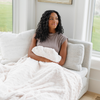 A woman smiles holds a ivory luxurious patterned faux fur extra large throw blanket that is a Saranoni blanket. This ultra-soft, cozy blanket adds a touch of elegance and warmth to any space, perfect as a soft oversized blanket or fluffy blanket for lounging. Ideal for those seeking a high-quality artificial fur blanket or luxury blanket, this versatile and stylish soft blanket enhances both comfort and decor. Shop the best blankets and throws for ultimate relaxation and cozy vibes.