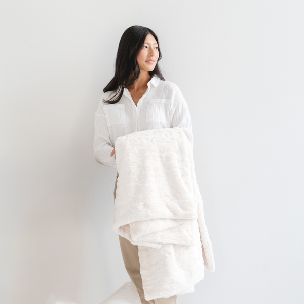 A woman holds an ivory luxurious patterned faux fur throw blanket that is a Saranoni blanket. This ultra-soft, plush throw blanket adds a touch of elegance and warmth to any space, perfect as a soft throw blanket or fluffy blanket for lounging. Ideal for those seeking a high-quality artificial fur blanket or luxury blanket, this versatile and stylish soft blanket enhances both comfort and decor. Shop the best blankets and throws for ultimate relaxation and cozy vibes.