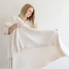 A woman holds a Bamboni® blanket by Saranoni. This ultra-soft blanket is a ivory blanket and made from a premium blend of bamboo rayon and poly microfiber, offering a lightweight, breathable, and fluffy feel. Perfect as a extra large blanket, luxury blanket, or soft blanket, it adds warmth and elegance to any living room, bedroom, or home décor setting. Designed for ultimate comfort, this buttery-soft Saranoni blanket is ideal for gifting. Enjoy this cozy blanket for years to come! 