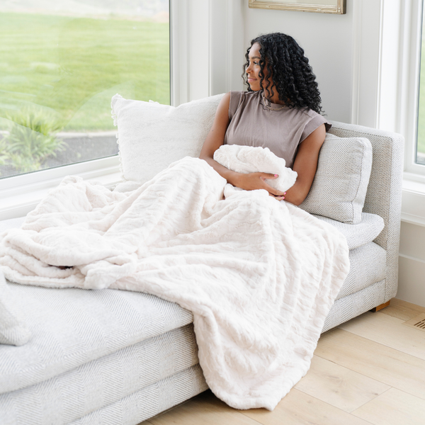 A woman holds a ivory luxurious patterned faux fur extra large throw blanket that is a Saranoni blanket. This ultra-soft, cozy blanket adds a touch of elegance and warmth to any space, perfect as a soft oversized blanket or fluffy blanket for lounging. Ideal for those seeking a high-quality artificial fur blanket or luxury blanket, this versatile and stylish soft blanket enhances both comfort and decor. Shop the best blankets and throws for ultimate relaxation and cozy vibes.