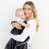 Mom stands holding baby boy snuggled with Charcoal lush blanket. 