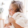 A little girl holds a Luxury Toddler Natural (off-white) Colored Lush Saranoni Blanket. The soft blanket is a toddler blanket or baby blanket.