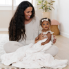 A mother wraps her daughter in a Luxury Toddler Natural (off-white) Colored Lush Saranoni Blanket. The soft blanket is a toddler blanket or baby blanket.