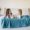 Two little girls and a Mineral Blue Lush XL Saranoni blanket, designed for oversized comfort and featuring a buttery soft, plush texture. This luxurious Saranoni blanket is perfect for cozy evenings, reading, or home decor. The Saranoni blanket adds warmth, style, and unmatched softness, making it an ideal gift or essential for ultimate relaxation. The soft blanket is a luxury blanket and a Saranoni blanket. 