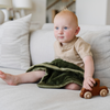 A baby boy sits with a Mini Fern Colored Lush Saranoni Blanket. The soft blanket is a small blanket and a baby blanket.