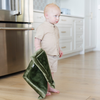 A baby boy holds a Mini Fern Colored Lush Saranoni Blanket. The soft blanket is a small blanket and a baby blanket.