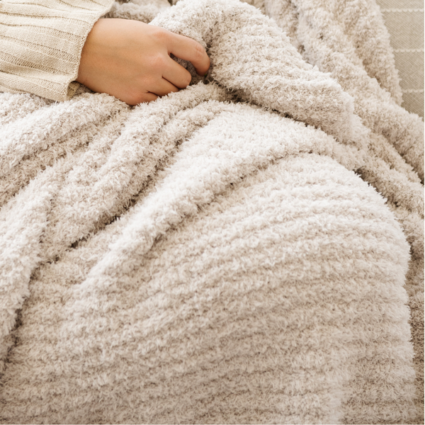 A luxurious ribbed Bamboni® blanket by Saranoni, the blanket is a very light tan. This ultra-soft blanket is crafted from bamboo rayon and poly microfiber, making it lightweight, breathable, and fluffy. Ideal as a cozy blanket, throw blanket, luxury blanket, soft blanket, or stylish home accent, this Saranoni blanket brings warmth, comfort, and timeless elegance to any living room or bedroom.