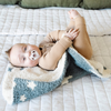 A happy baby boy with a double-layer Bamboni® baby blanket. The plush, breathable blanket features a two-tone blue and cream star design, offering ultimate softness and warmth. Made from Saranoni’s signature stretchy, cloud-like Bamboni® fabric, this luxury baby blanket provides comfort for naps, tummy time, and on-the-go snuggles. The perfect blend of warmth and breathability, it’s a must-have for parents seeking high-quality, ultra-soft blankets. The soft blanket is a mini blanket and Saranoni blanket. 