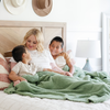 A mother and her kids sit with a Bamboni® blanket by Saranoni. This ultra-soft blanket is a light green blanket and made from a premium blend of bamboo rayon and poly microfiber, offering a lightweight, breathable, and fluffy feel. Perfect as a extra large blanket, luxury blanket, or soft blanket, it adds warmth and elegance to any living room, bedroom, or home décor setting. Designed for ultimate comfort, this buttery-soft Saranoni blanket is ideal for gifting. Enjoy this cozy blanket for years to come!