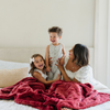 A mother and her son and daughter with a red luxurious patterned faux fur throw blanket that is a Saranoni blanket. This ultra-soft, plush throw blanket adds a touch of elegance and warmth to any space, perfect as a soft throw blanket or fluffy blanket for lounging. Ideal for those seeking a high-quality artificial fur blanket or luxury blanket, this versatile and stylish soft blanket enhances both comfort and decor. Shop the best blankets and throws for ultimate relaxation and cozy vibes.