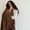 A woman holds a brown luxurious patterned faux fur extra large throw blanket that is a Saranoni blanket. This ultra-soft, cozy blanket adds a touch of elegance and warmth to any space, perfect as a soft extra large throw blanket or fluffy blanket for lounging. Ideal for those seeking a high-quality artificial fur blanket or luxury blanket, this versatile and stylish soft blanket enhances both comfort and decor. Shop the best blankets and throws for ultimate relaxation and cozy vibes.