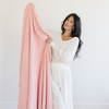 A woman holds up a Bamboni® blanket by Saranoni. This ultra-soft blanket is a peach blanket and made from a premium blend of bamboo rayon and poly microfiber, offering a lightweight, breathable, and fluffy feel. Perfect as a extra large blanket, luxury blanket, or soft blanket, it adds warmth and elegance to any living room, bedroom, or home décor setting. Designed for ultimate comfort, this buttery-soft Saranoni blanket is ideal for gifting. Enjoy this cozy blanket for years to come!