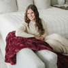 A woman sits with a pomegranate luxurious patterned faux fur throw blanket that is a Saranoni blanket. This ultra-soft, plush throw blanket adds a touch of elegance and warmth to any space, perfect as a soft throw blanket or fluffy blanket for lounging. Ideal for those seeking a high-quality artificial fur blanket or luxury blanket, this versatile and stylish soft blanket enhances both comfort and decor. Shop the best blankets and throws for ultimate relaxation and cozy vibes.