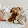 A delightful arrangement of three plush stuffed animals—a white lamb, a brown dog, and a cream-colored bear—sits on a soft quilt. The adorable textures and colors of these cuddly toys make them perfect companions for children. This charming display highlights the importance of quality stuffed animals in creating a warm and inviting play environment for kids, making it ideal for parents searching for comforting toys for their little ones.