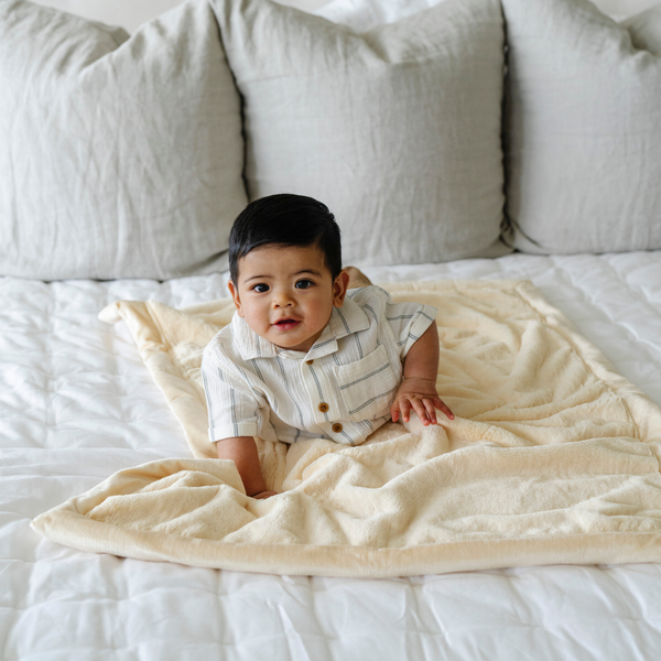 A baby boy lays on a Receiving Chiffon (light yellow) Colored Lush Saranoni Blanket. The soft blanket is a small blanket and a baby blanket or toddler blanket.