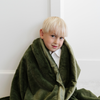 A little boy wrapped in a Receiving Fern Colored Lush Saranoni Blanket. The soft blanket is a small blanket and a baby blanket or toddler blanket.