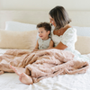 A mother and her son sit with a rouge colored extra large patterned faux fur throw Saranoni Luxury Blanket. The soft blanket is an oversized throw blanket.