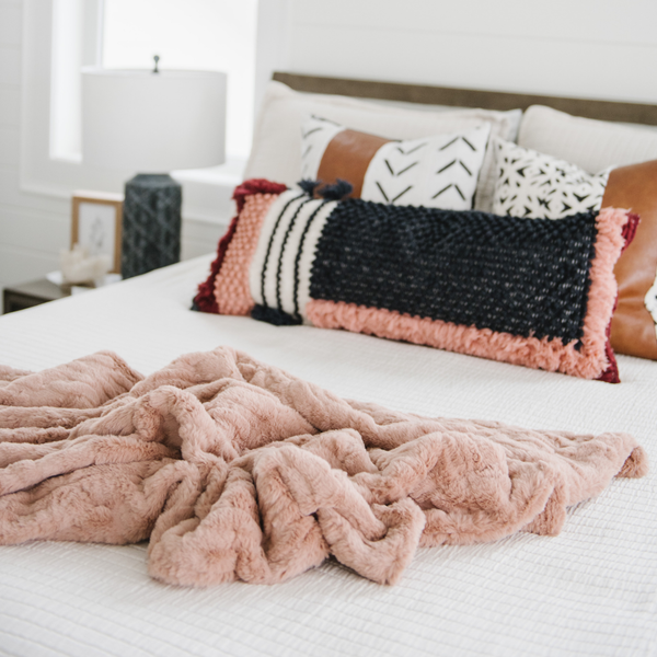 A rouge luxurious patterned faux fur throw blanket that is a Saranoni blanket is draped on a bed. This ultra-soft, plush throw blanket adds a touch of elegance and warmth to any space, perfect as a soft throw blanket or fluffy blanket for lounging. Ideal for those seeking a high-quality artificial fur blanket or luxury blanket, this versatile and stylish soft blanket enhances both comfort and decor. Shop the best blankets and throws for ultimate relaxation and cozy vibes.