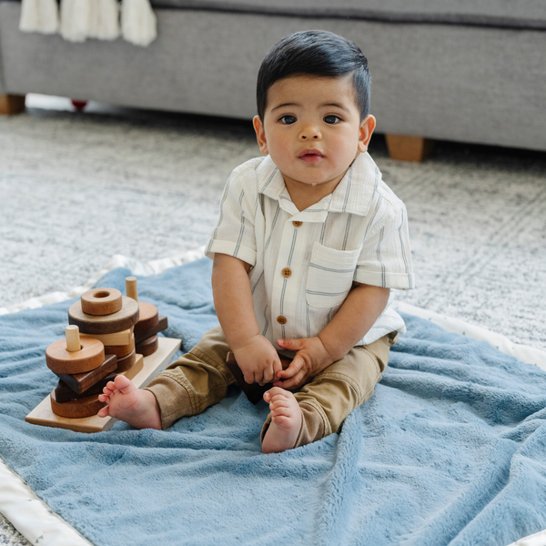 Boy playing on a blue receiving blanket. 