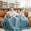 A father and his sons sit under a Bamboni® blanket by Saranoni. This ultra-soft blanket is a light blue blanket and made from a premium blend of bamboo rayon and poly microfiber, offering a lightweight, breathable, and fluffy feel. Perfect as a extra large blanket, luxury blanket, or soft blanket, it adds warmth and elegance to any living room, bedroom, or home décor setting. Designed for ultimate comfort, this buttery-soft Saranoni blanket is ideal for gifting. Enjoy this cozy blanket for years to come!