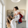 A mother plays with her little boy while holding a mini blanket with a Superman™ icon on it. The soft blanket is light blue and red. This kids blanket is a luxury blanket and a Saranoni blanket. The blanket is also a double-layer Bamboni® blanket. 