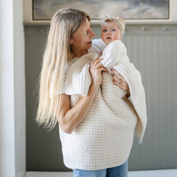 A mother holds her little girl in a buttery-soft Saranoni blanket, featuring a breathable, plush waffle texture in a soothing white hue. This luxury receiving blanket is the best baby blanket as a  newborn blanket, infant blanket, baby blanket, or toddler blanket—perfect as a cozy blanket for snuggles or a must-have infant blanket. Designed for softness and comfort, this plush baby blanket makes an ideal baby gift or gift for new moms. Enjoy this luxury blanket!