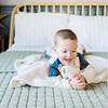 A little boy has a buttery-soft Saranoni blanket, featuring a breathable, plush waffle texture in a soothing white hue. This luxury toddler blanket is the best kids blanket as a baby blanket or toddler blanket—perfect as a cozy blanket for snuggles or a must-have infant blanket. Designed for softness and comfort, this plush toddler blanket makes an ideal toddler gift. Enjoy this luxury blanket!