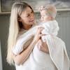 A mother holds her baby girl in a buttery-soft Saranoni blanket, featuring a breathable, plush waffle texture in a soothing white hue. This luxury toddler blanket is the best kids blanket as a baby blanket or toddler blanket—perfect as a cozy blanket for snuggles or a must-have infant blanket. Designed for softness and comfort, this plush toddler blanket makes an ideal toddler gift. Enjoy this luxury blanket!