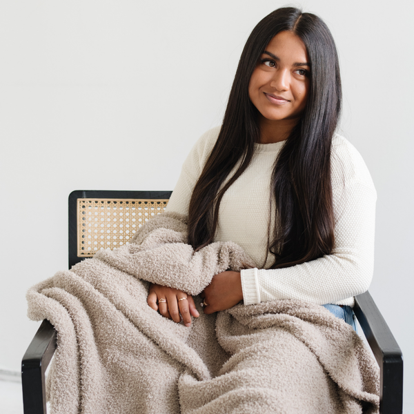 A woman holds a Bamboni® blanket by Saranoni. This ultra-soft blanket is a taupe blanket and made from a premium blend of bamboo rayon and poly microfiber, offering a lightweight, breathable, and fluffy feel. Perfect as a throw blanket, luxury blanket, plush throw, or soft blanket, it adds warmth and elegance to any living room, bedroom, or home décor setting. Designed for ultimate comfort, this buttery-soft Saranoni blanket is ideal for gifting. Enjoy this cozy blanket for years to come!