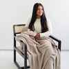 A woman sits holding a Bamboni® blanket by Saranoni. This ultra-soft blanket is a taupe blanket and made from a premium blend of bamboo rayon and poly microfiber, offering a lightweight, breathable, and fluffy feel. Perfect as a throw blanket, luxury blanket, plush throw, or soft blanket, it adds warmth and elegance to any living room, bedroom, or home décor setting. Designed for ultimate comfort, this buttery-soft Saranoni blanket is ideal for gifting. Enjoy this cozy blanket for years to come!