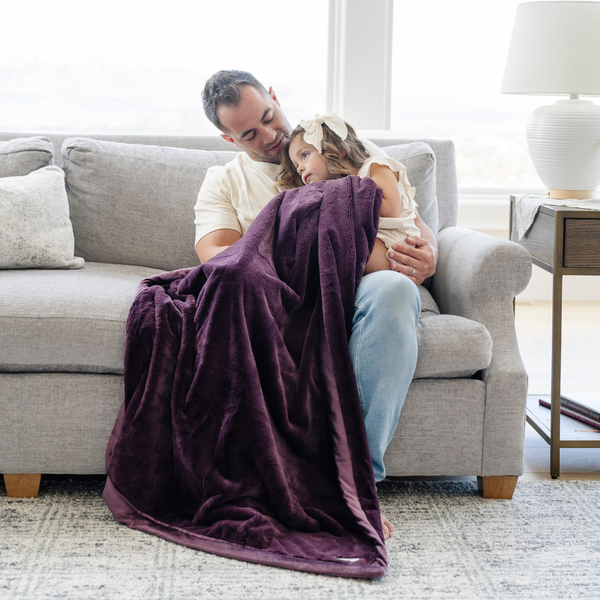 A father and daughter sit with a Toddler Aubergine (deep purple) Colored Lush Luxury Saranoni Blanket. The soft blanket is a baby blanket or toddler blanket.