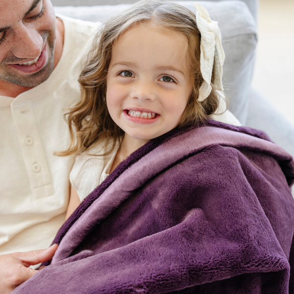 A father and daughter sit with a Toddler Aubergine (deep purple) Colored Lush Luxury Saranoni Blanket. The soft blanket is a baby blanket or toddler blanket.