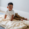 A little boy sits on a Toddler Chiffon (light yellow) Colored Lush Luxury Saranoni Blanket. The soft blanket is a baby blanket or toddler blanket.