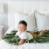 A little boy lays on a Toddler Fern Colored Lush Luxury Saranoni Blanket. The soft blanket is a baby blanket or toddler blanket.