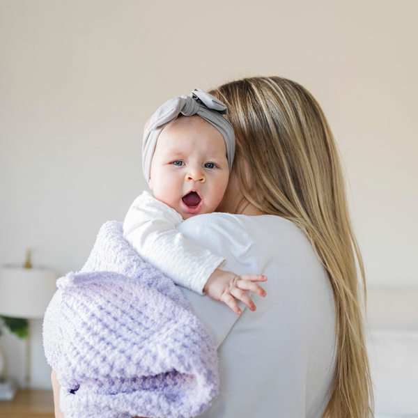 A mother holds her baby girl and a buttery-soft Saranoni blanket, featuring a breathable, plush waffle texture in a soothing light purple hue. This luxury mini blanket is the best baby blanket as a newborn blanket and infant blanket—perfect as a cozy blanket for snuggles or a must-have infant blanket. Designed for softness and comfort, this plush baby blanket makes an ideal baby boy gift or gift for new moms. Enjoy this luxury blanket! 