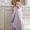 A little girl is wrapped in a buttery-soft Saranoni blanket, featuring a breathable, plush waffle texture in a soothing light purple hue. This luxury toddler blanket is the best kids blanket as a baby blanket or toddler blanket—perfect as a cozy blanket for snuggles or a must-have infant blanket. Designed for softness and comfort, this plush toddler blanket makes an ideal toddler gift. Enjoy this luxury blanket!